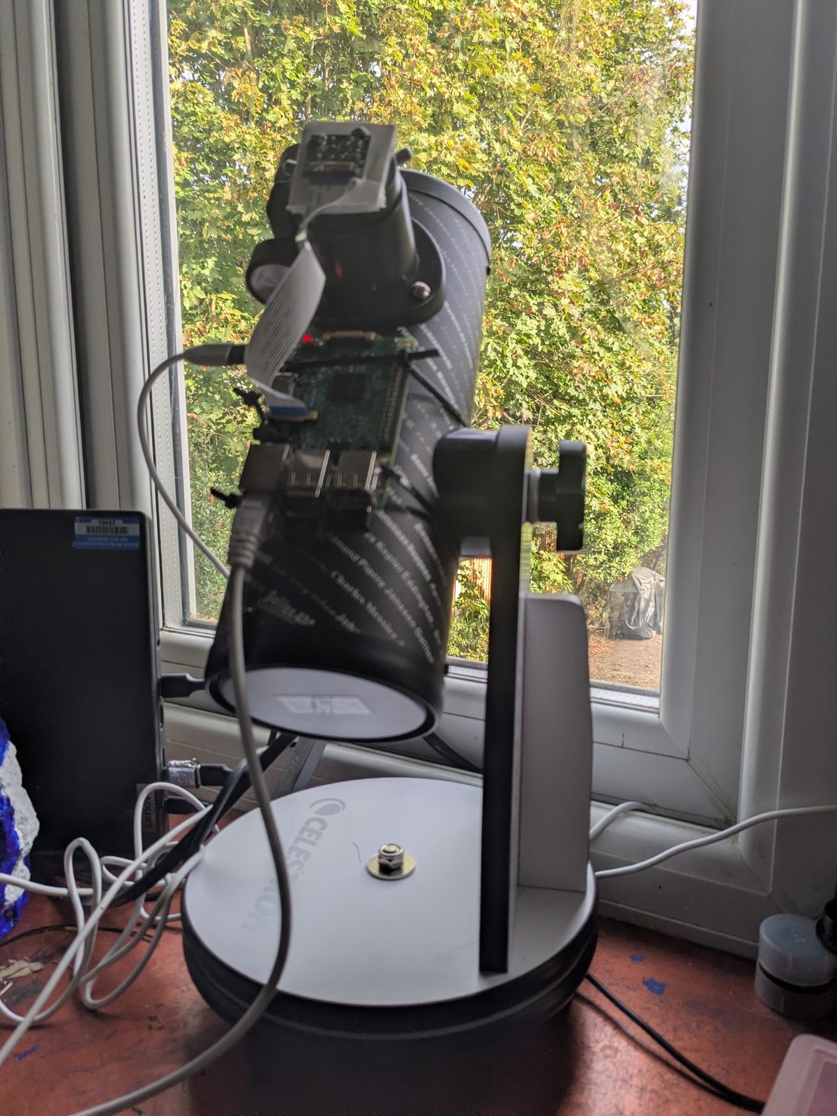 The FirstScope on a windowsill, a Raspberry Pi camera at the focuser and a Pi 3 cable-tied to the tube
